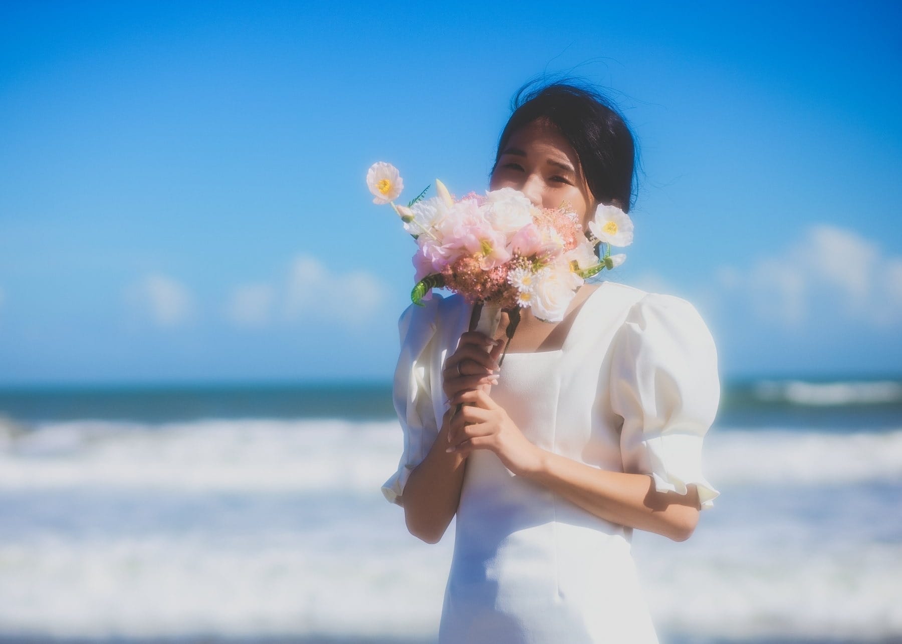 Bride holding a bouquet on the beach