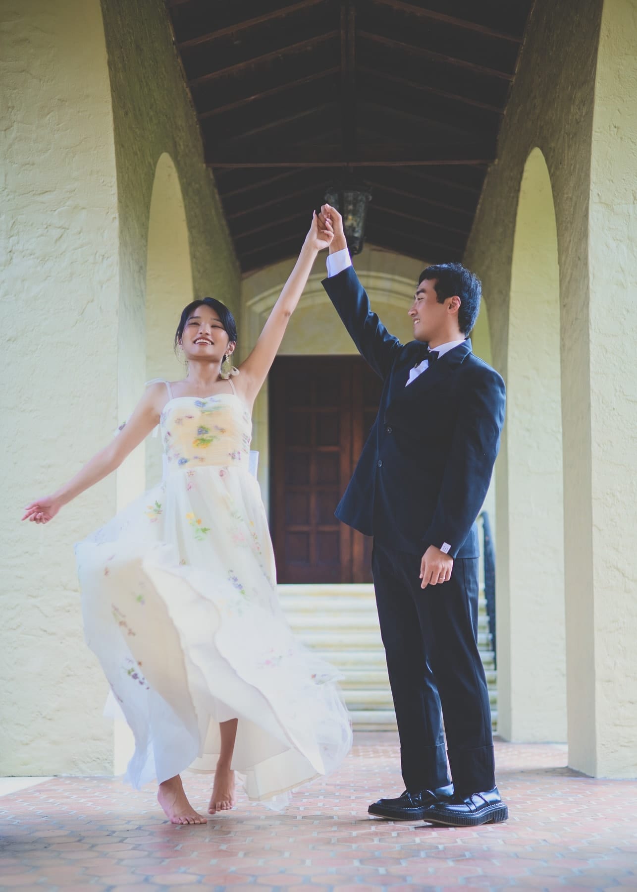 Bride twirling beneath the arcade as the groom holds her hand