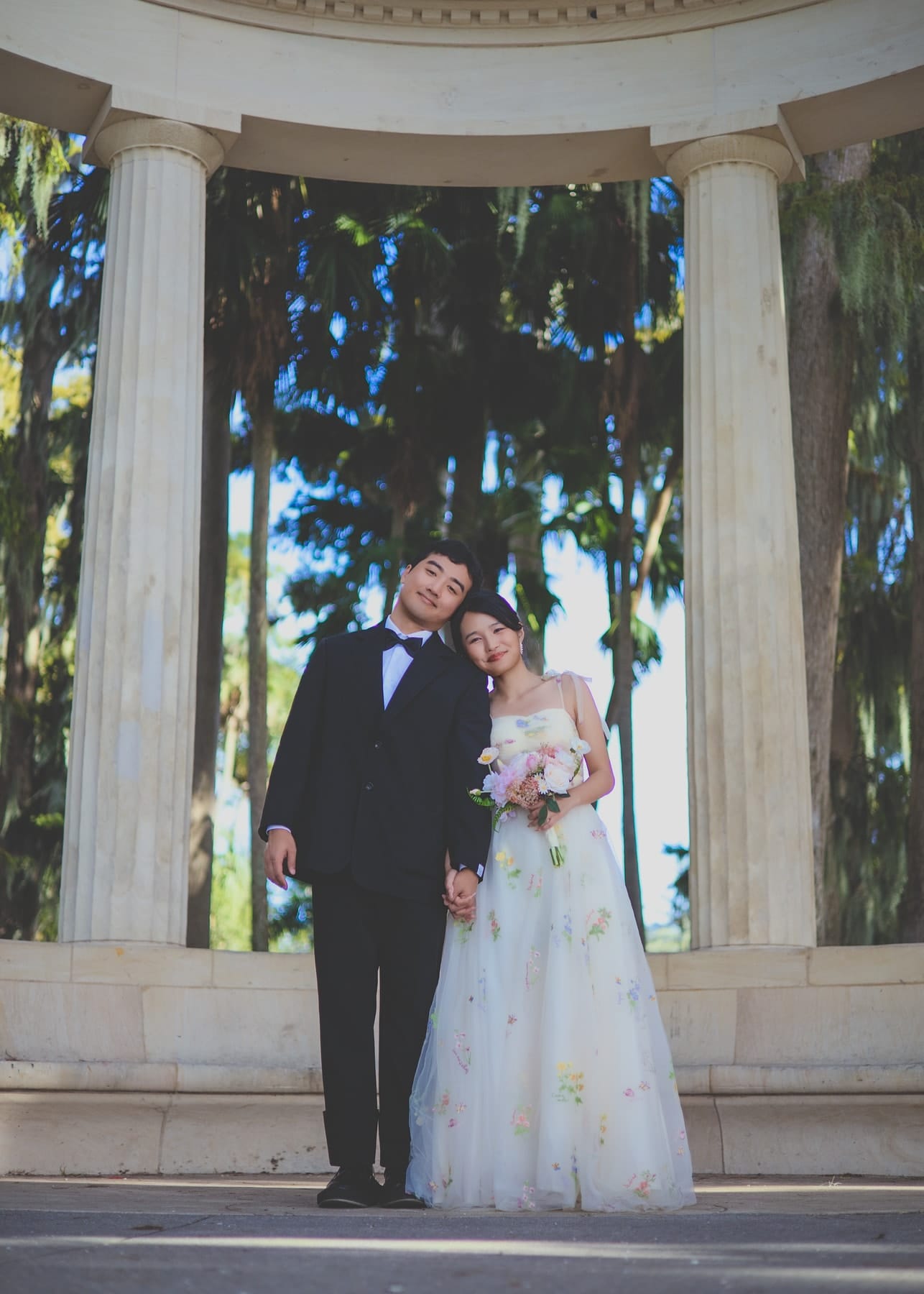 Couple standing together beneath a white columned pavilion