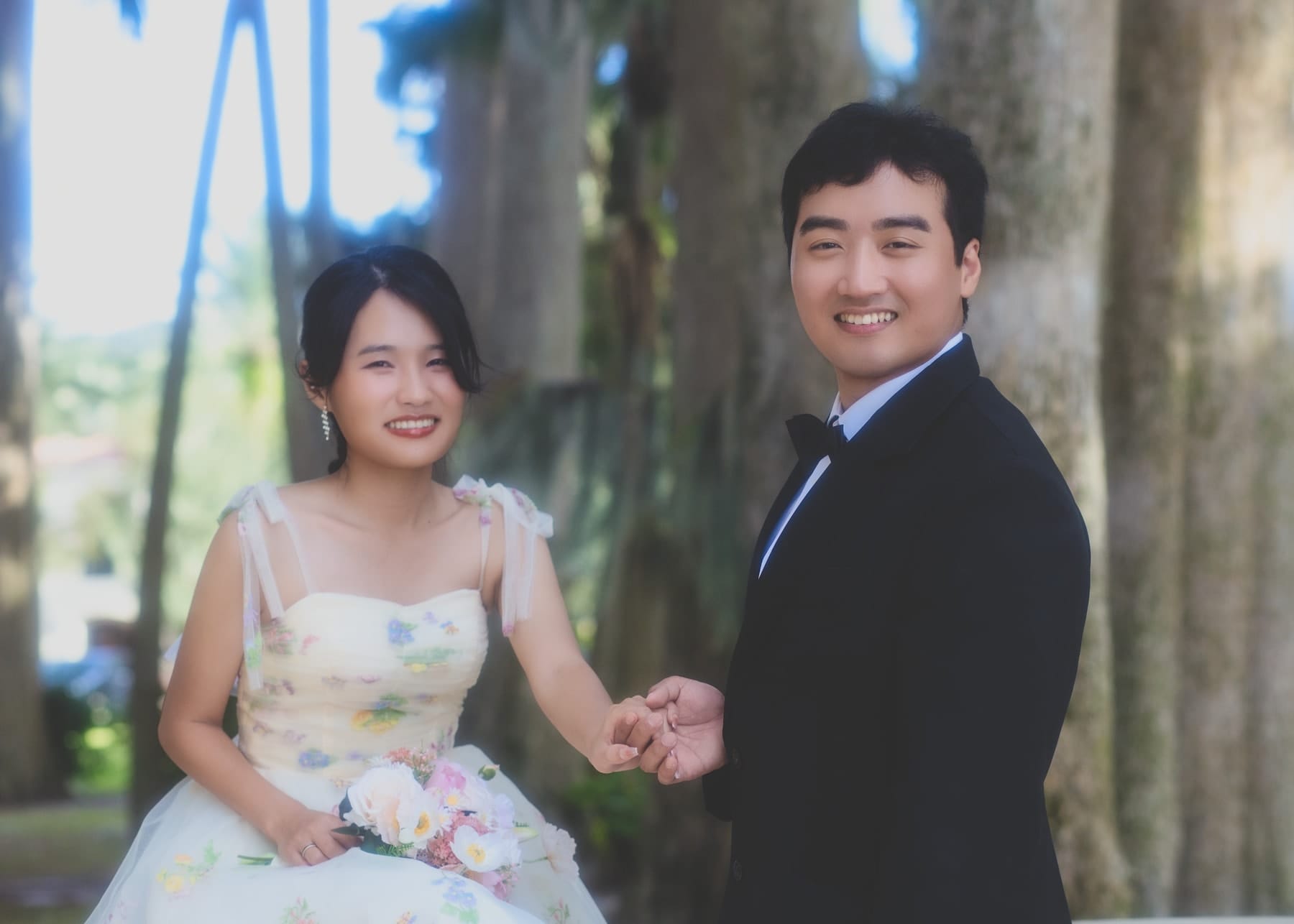 Couple holding hands among palm trunks