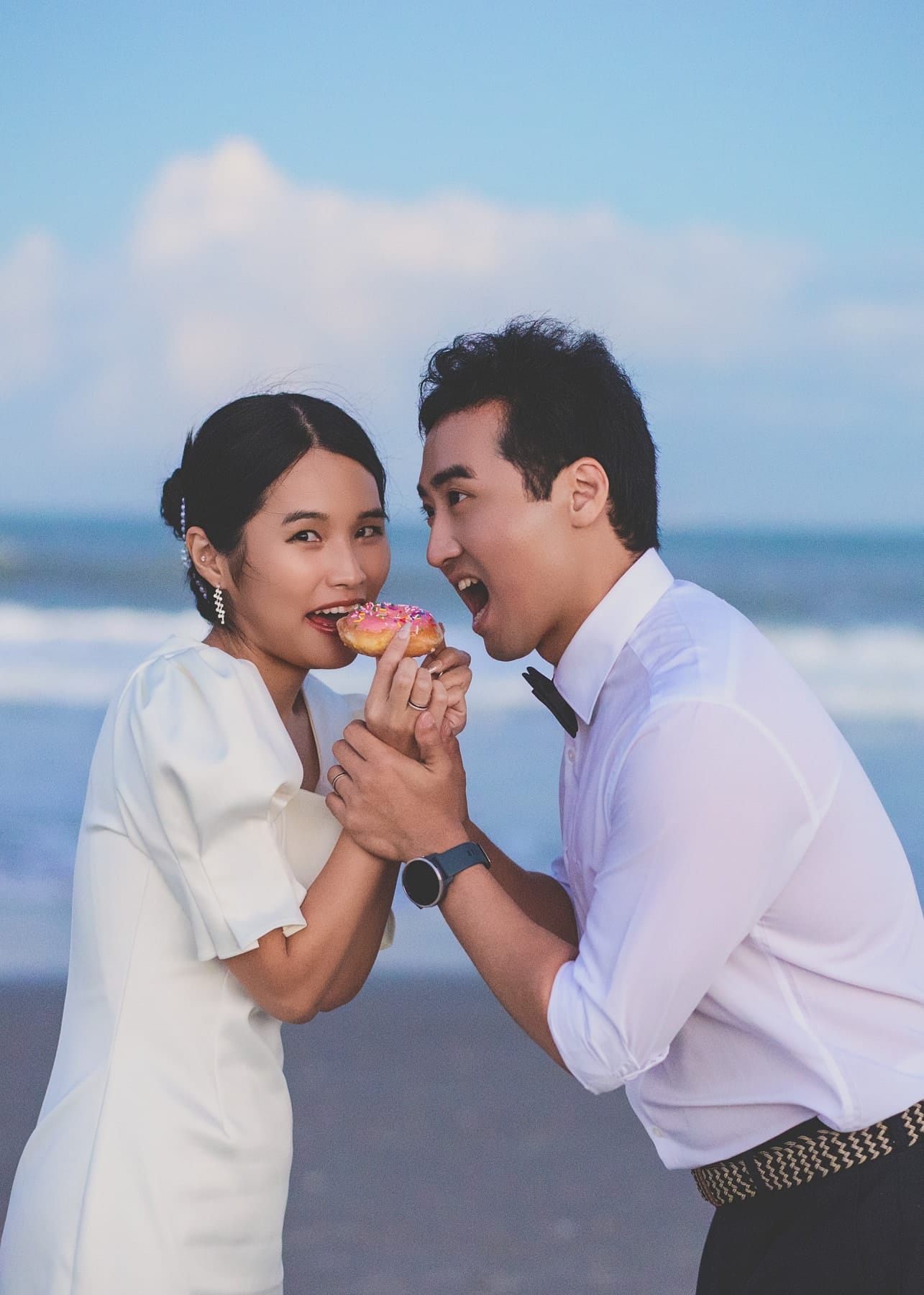 Couple sharing a donut by the sea