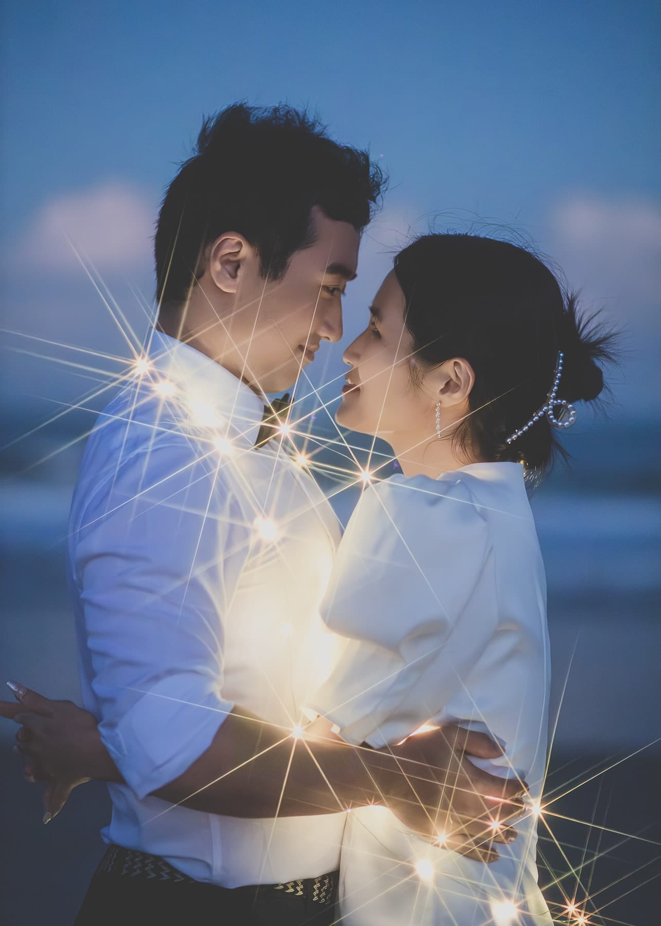 Couple face to face at blue hour among starburst lights