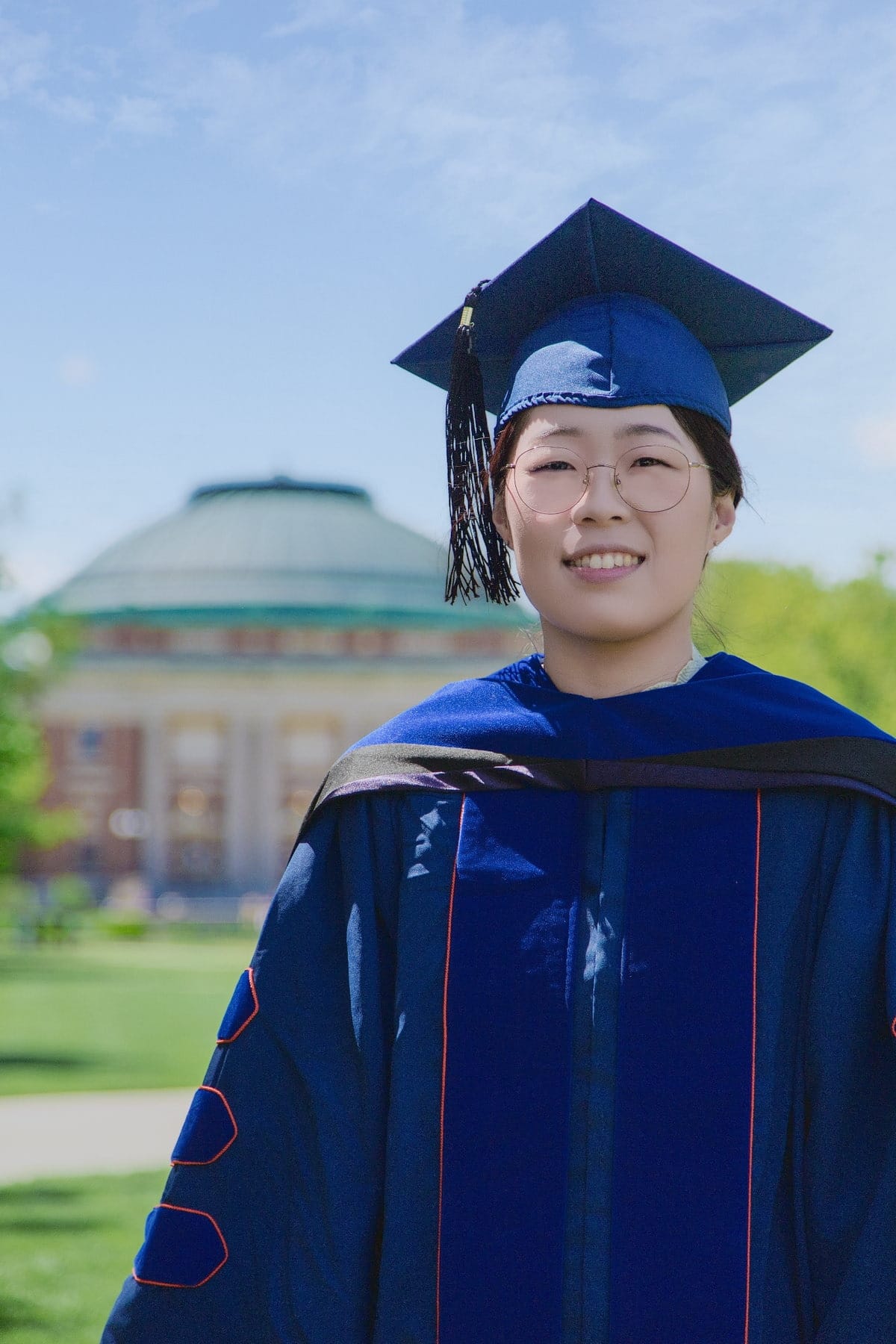 Graduation portrait framed by campus architecture and open sky