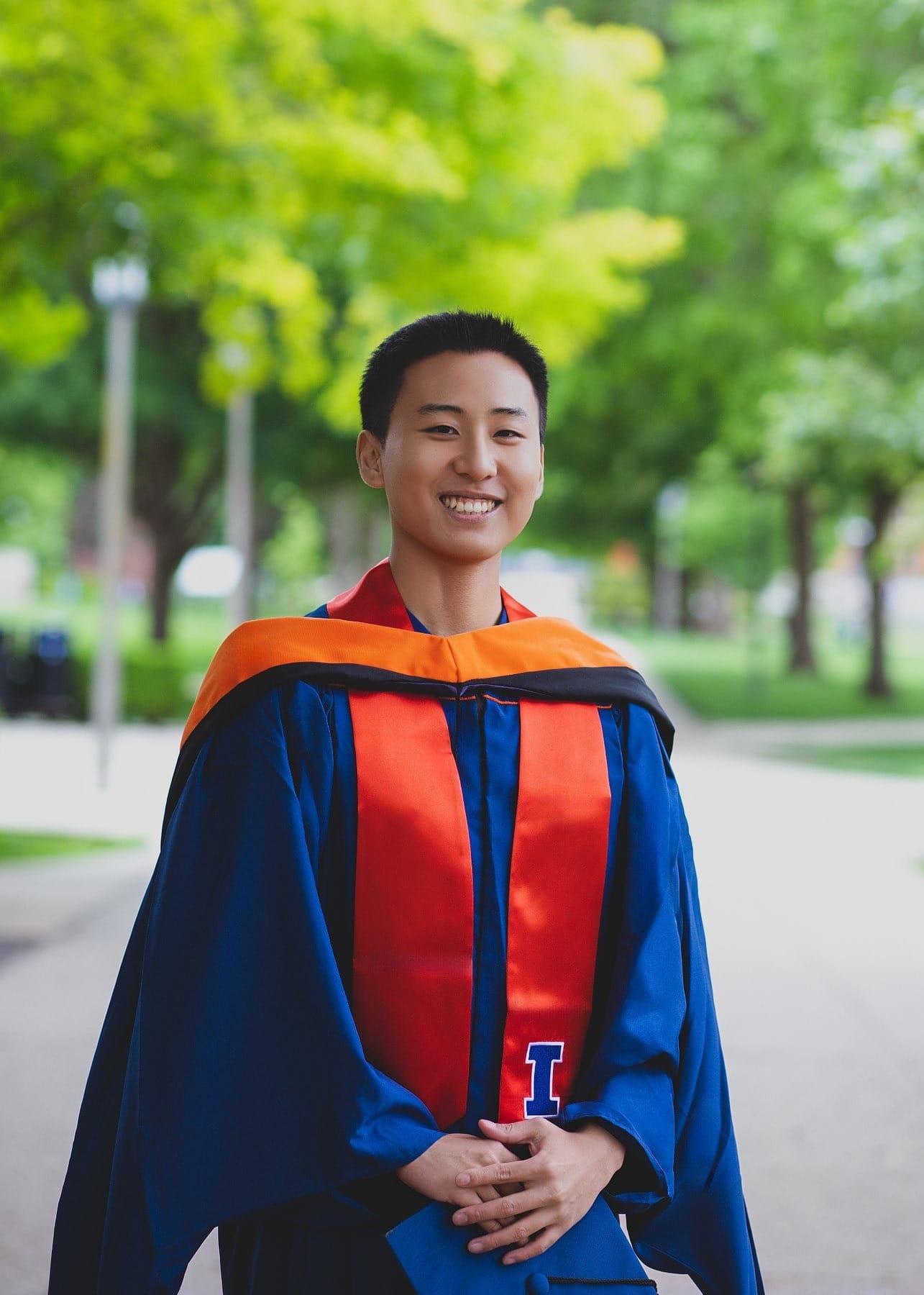 Graduate portrait on a green campus walkway