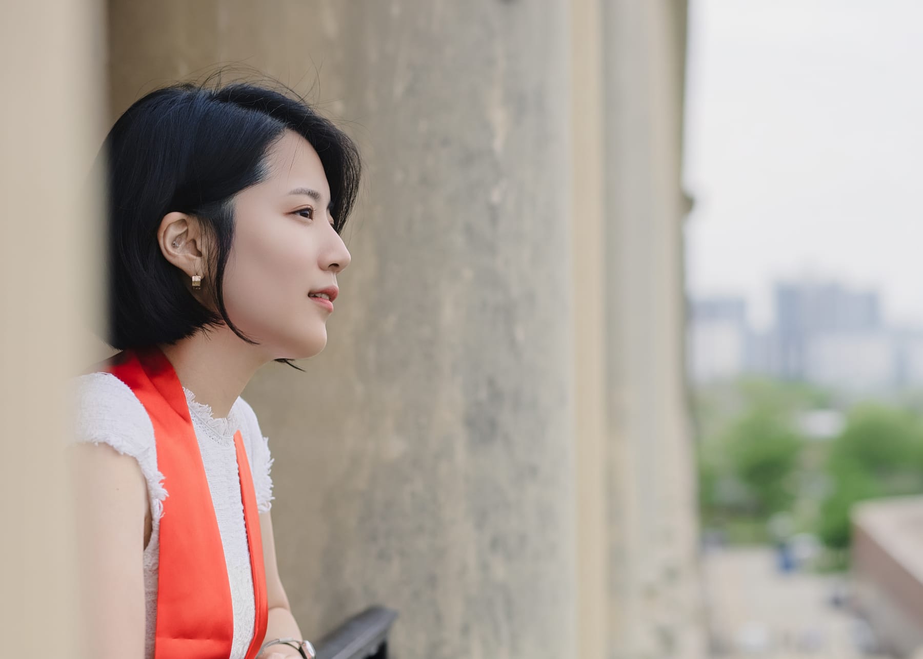 Side portrait of a graduate beside a stone column
