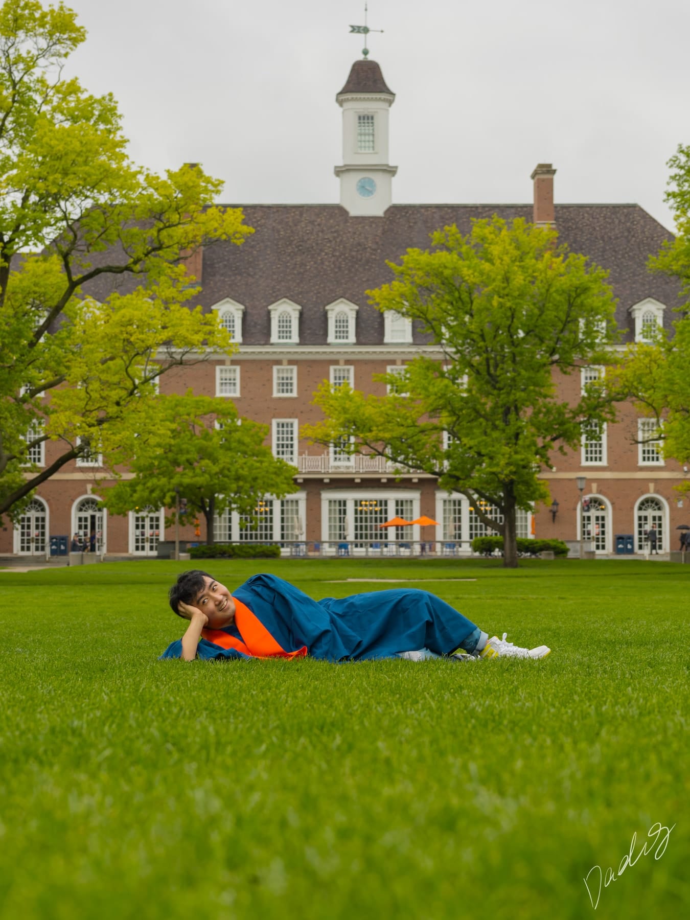 Graduate lying on the lawn before the hall