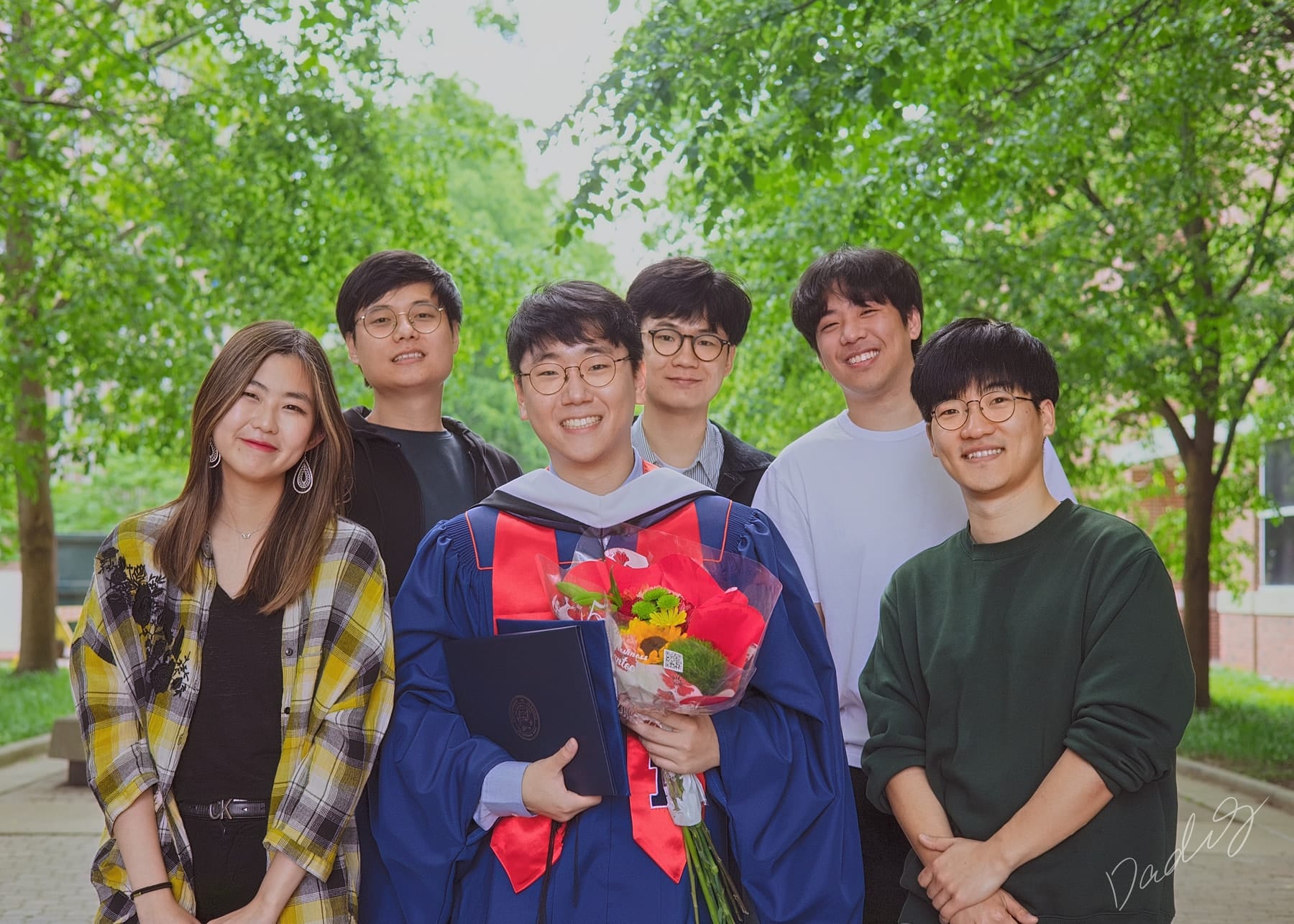 Graduate with five friends beneath trees