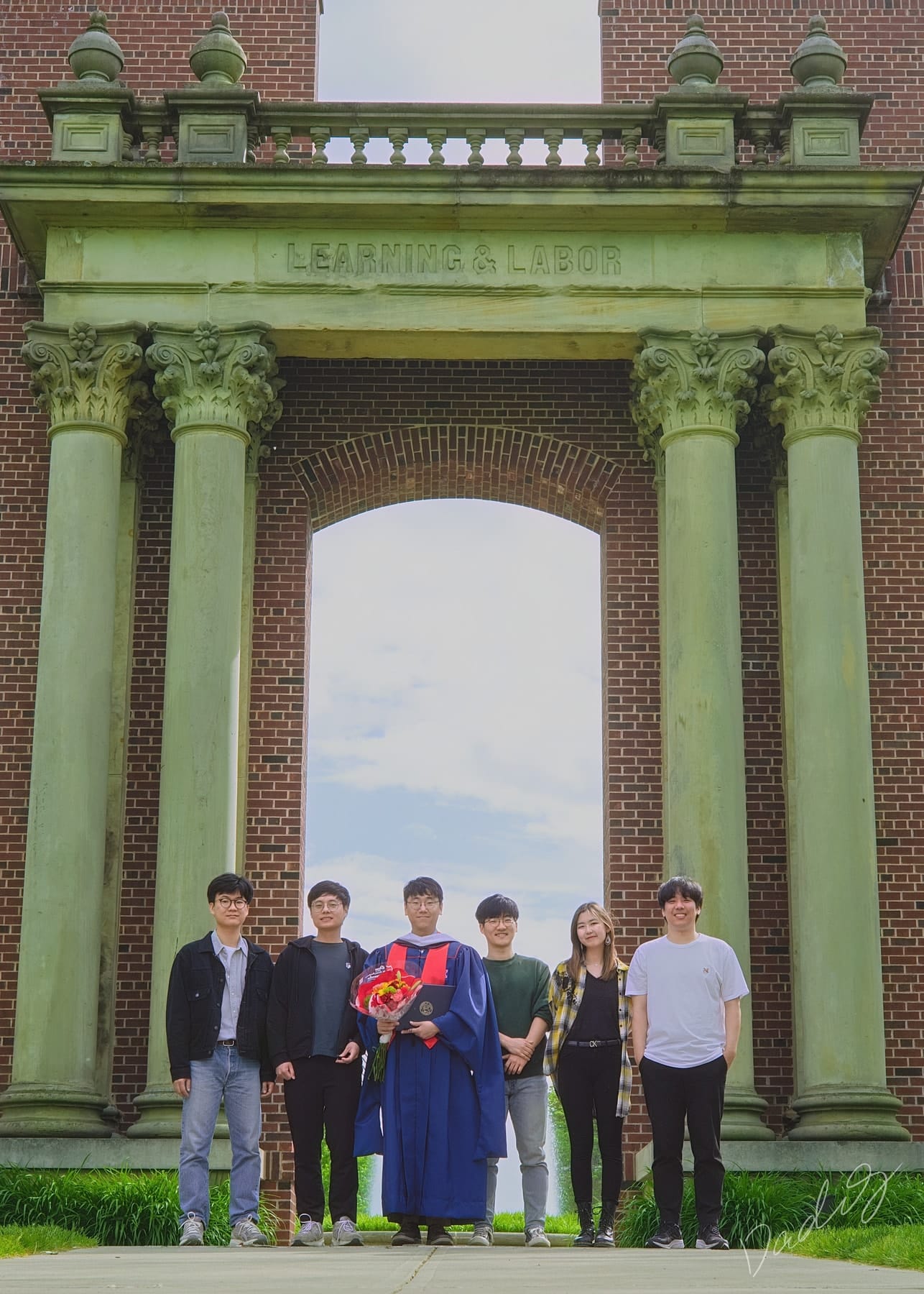 Graduate and friends beneath a tall brick arch