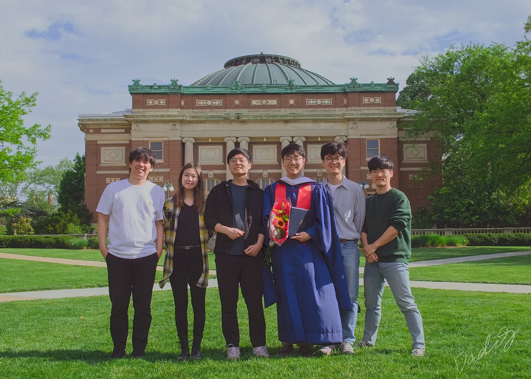 Graduate and friends on the lawn before the domed auditorium