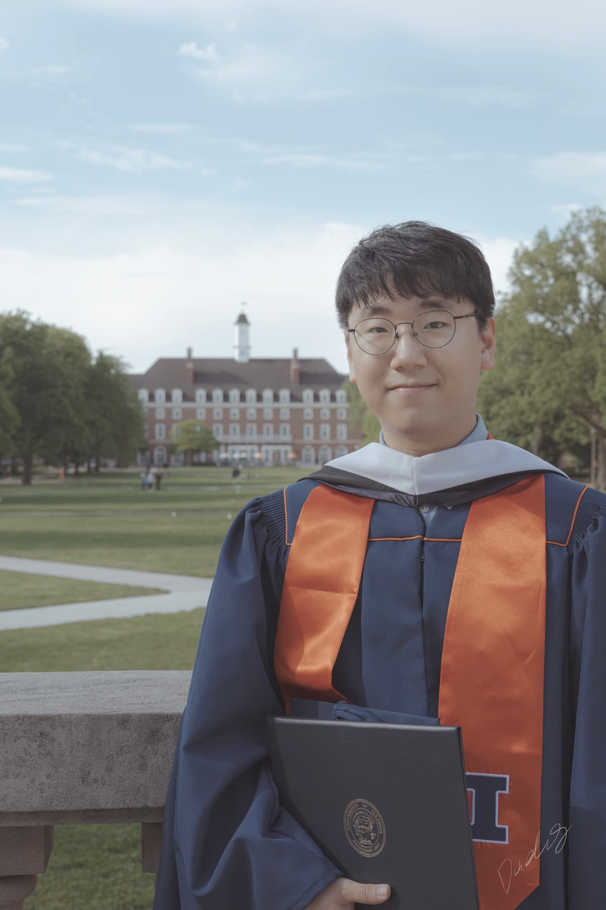 Graduate holding his diploma on the quad