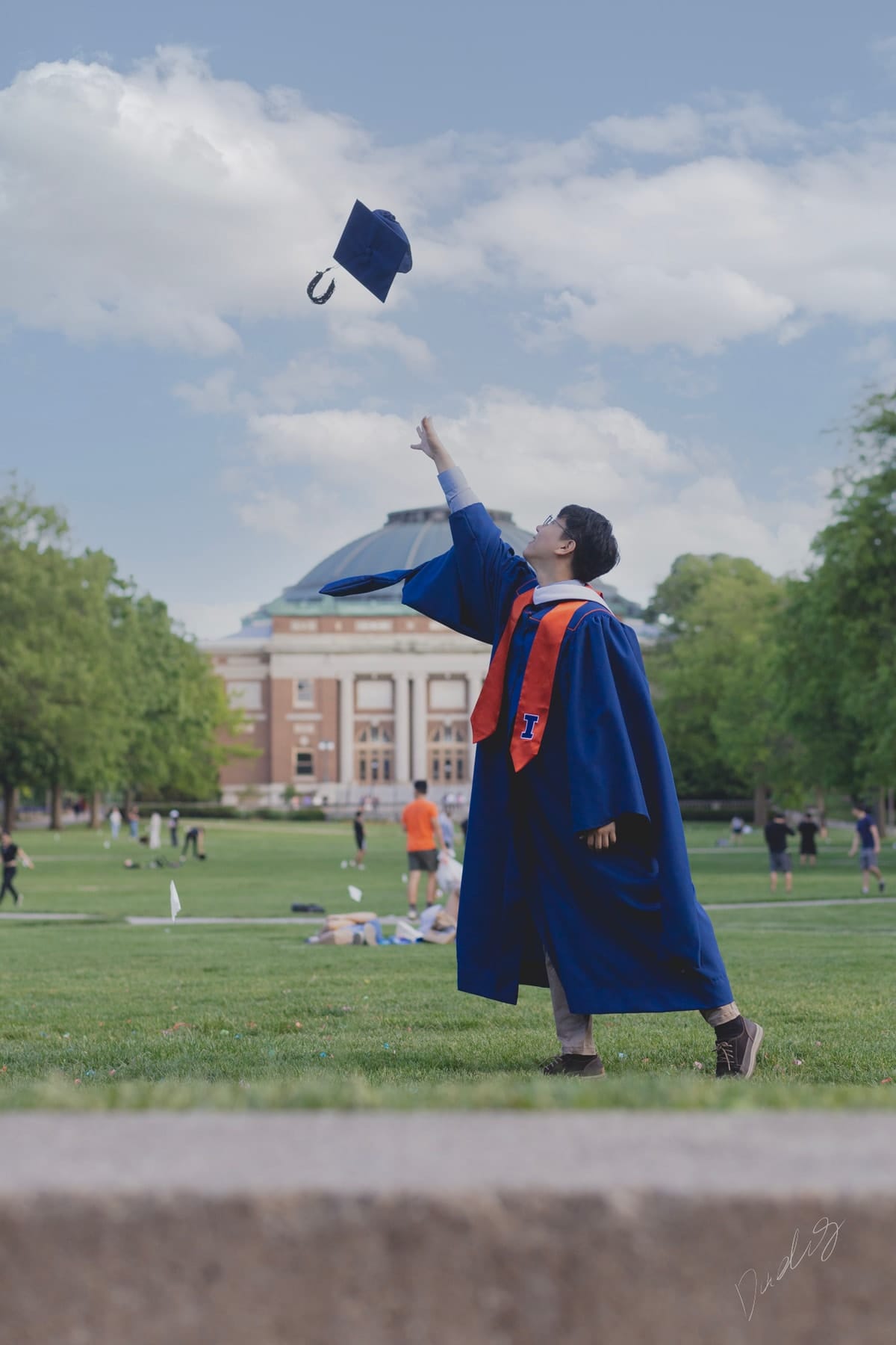 Graduate tossing his cap before the domed auditorium