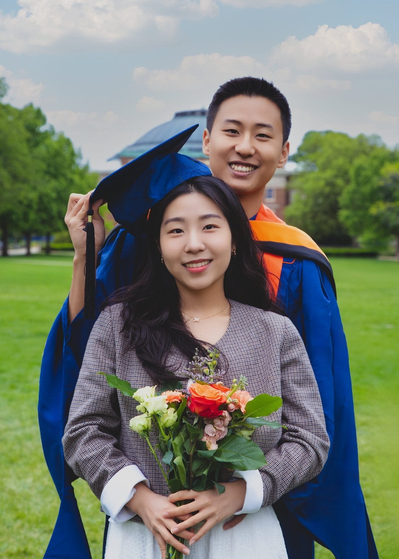 Graduate standing with his partner and flowers