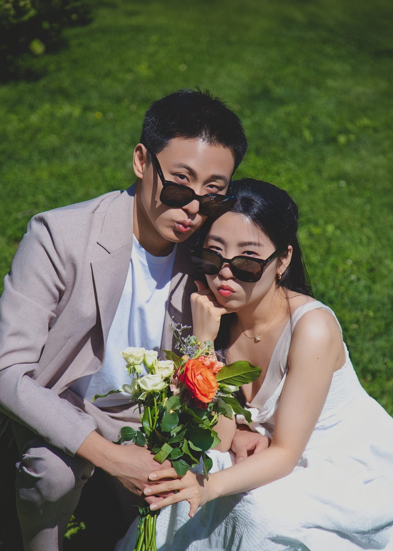 Playful couple portrait wearing sunglasses on the lawn