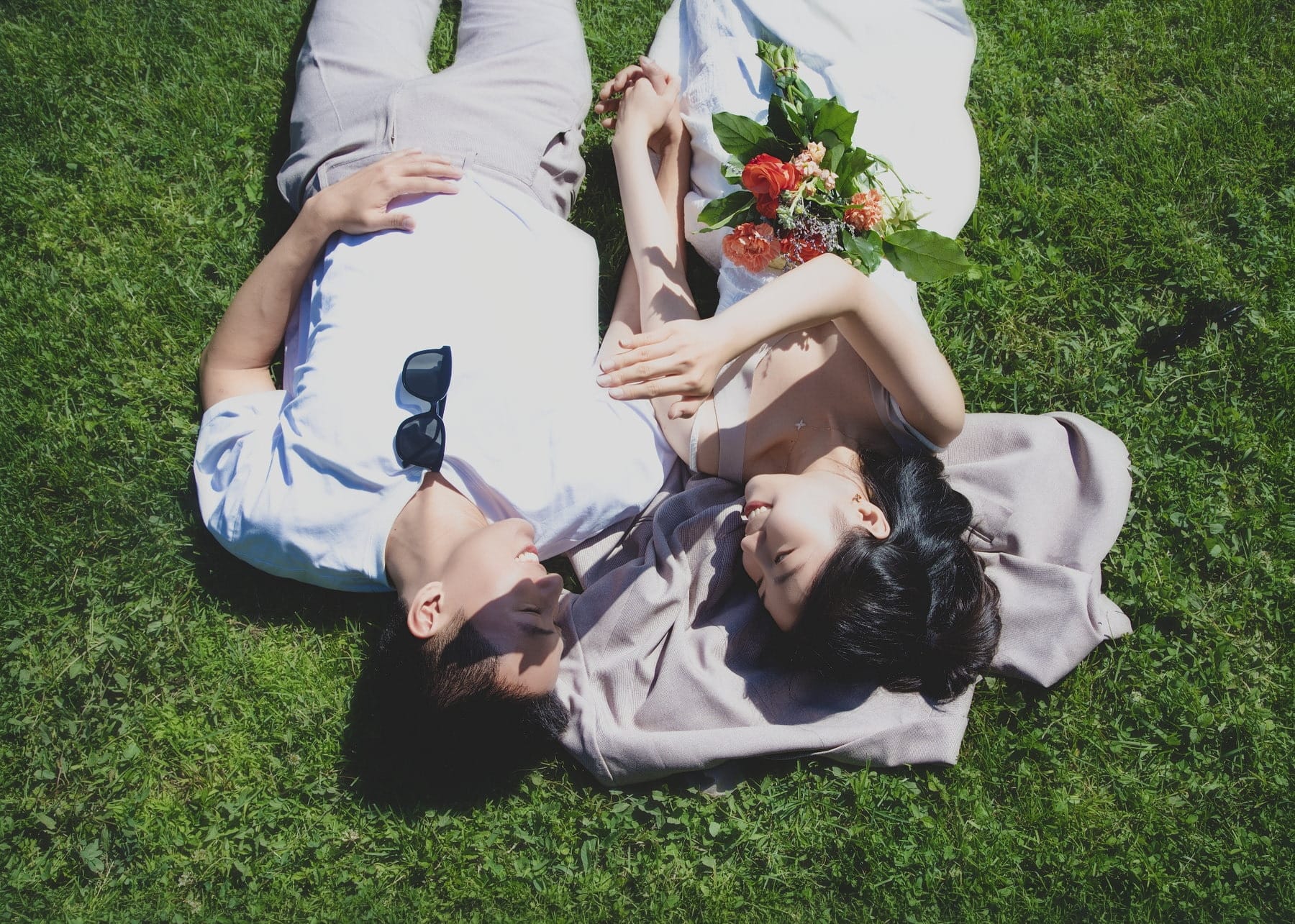 Couple lying together on the grass in bright summer light