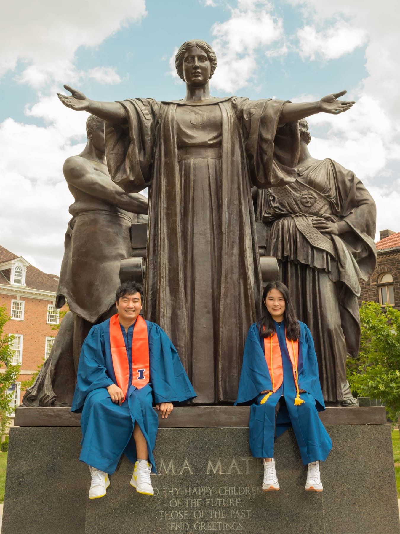 Graduates in orange stoles at the foot of the Alma Mater