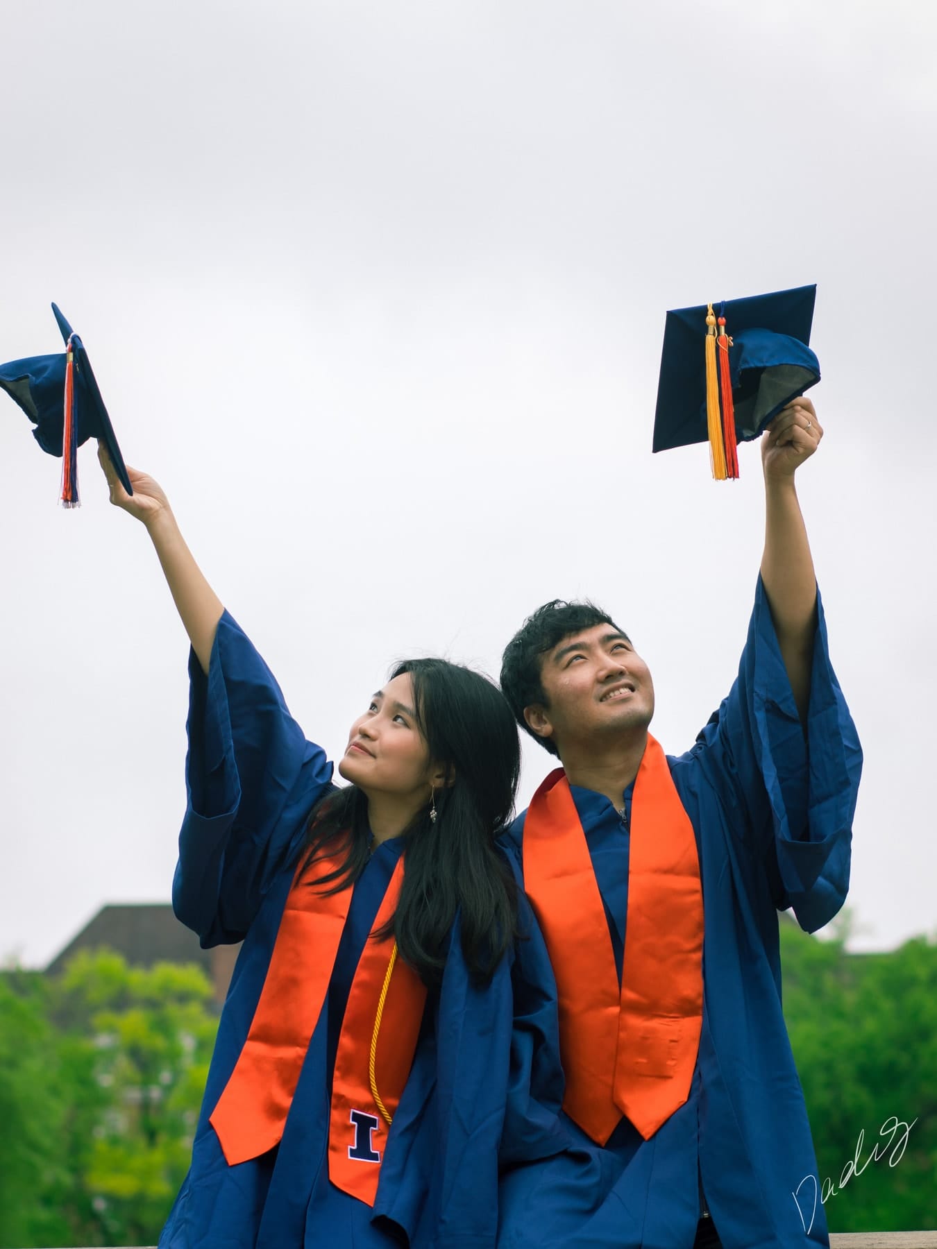 Two graduates raising their caps to the sky