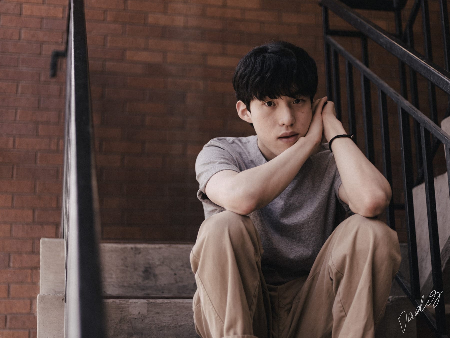 Seated on brick steps between iron railings
