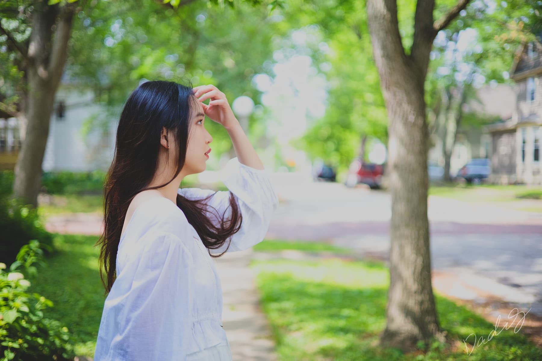 Shading her eyes on a tree-lined street